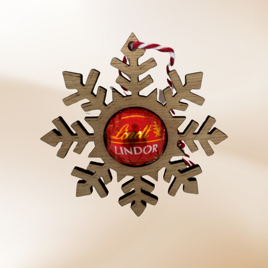 Wooden laser cut snowflake with a hole cut out for a Lindt Lindor round chocolate to give as a gift.  Finished with a red and white string to hang on the tree.